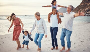 Familie cu 3 generații pe plajă, zâmbind și distrându-se, pentru a ilustra cum familiile nu vor mai fi la fel pe viitor