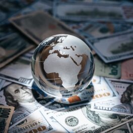 Glob pământesc transparent, pe un pat de dolari, pentru a ilustra țările cu cele mai mari datorii
