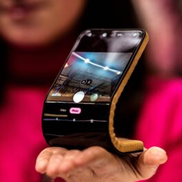 Ecranul Flexibil Motorola prezentat la MWC 2024, Barcelona, ținut în mână d eo femeie îmbrăcată în roz