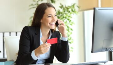 Femeie care stă la birou, vorbește la telefon, cu un card roșu, pentru a ilustra joburile cel mai bine plătite din viitor