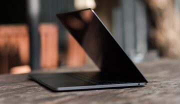 Laptop Lenovo negru, similar cu laptopul transparent, care stă pe un birou din lemn