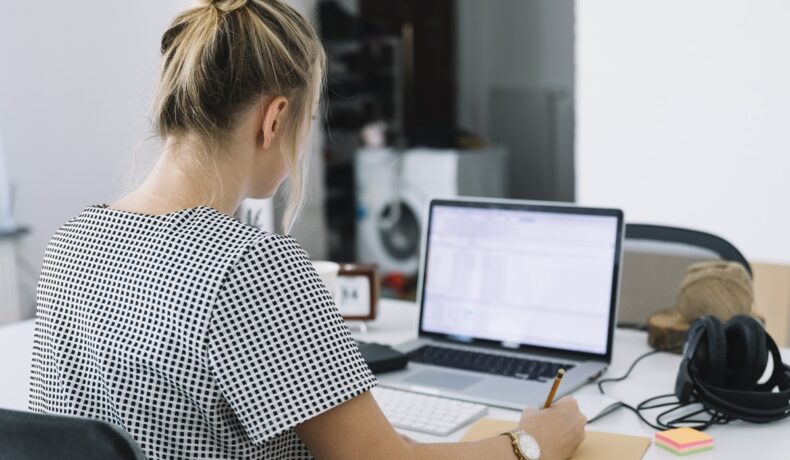 femeie blondă care stă în fața unui laptop, pentru a ilustra la ce trebuie să te gândești când alegi laptopul