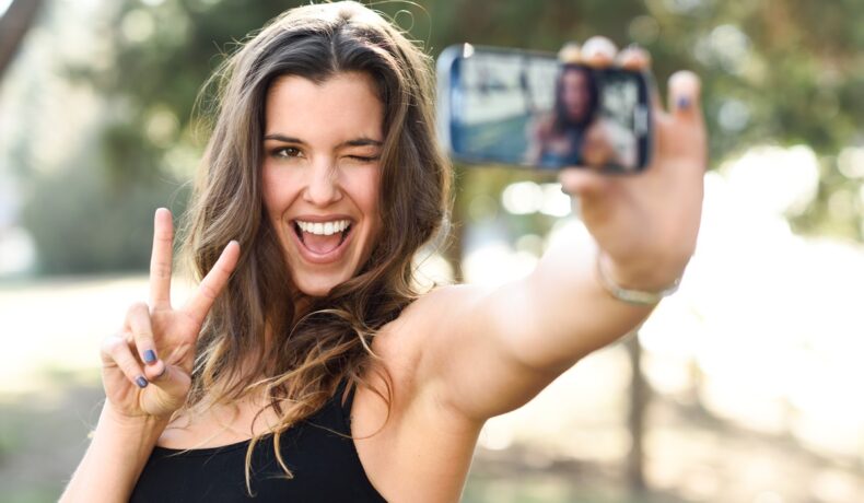 Femeie care îți face selfie, îmbrăcată în maiou negru, pentru a ilustra dacă pot copia hackerii amprentele din selfie-uri